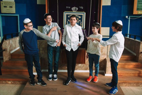 חתן בר המצווה לפני עלייתו לתורה לבוש חולצה מכופתרת ומכנס שחור